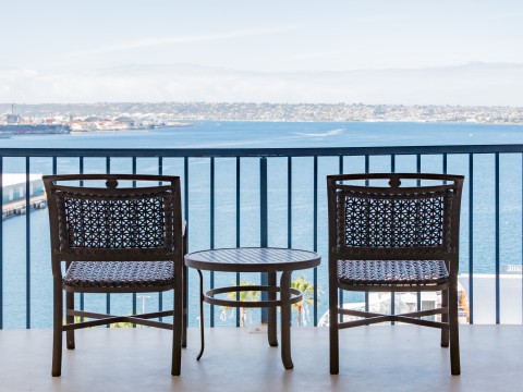 chairs and a table on a balcony overlooking a body of water