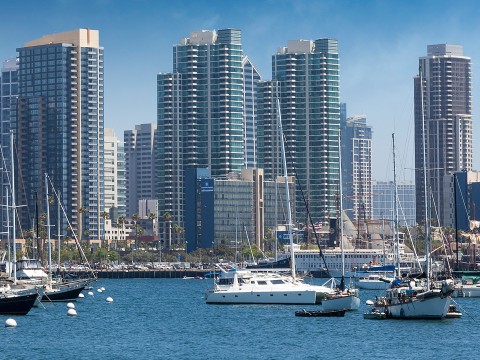 a group of boats in a body of water with tall buildings in the background