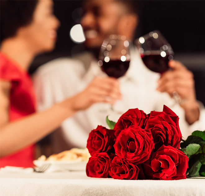 a bouquet of roses and wine glasses on a table