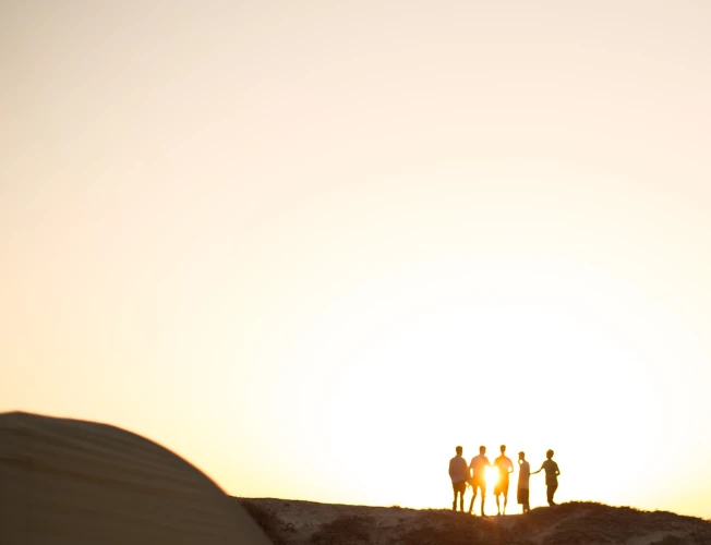 a group of friends standing on a hill during sunset