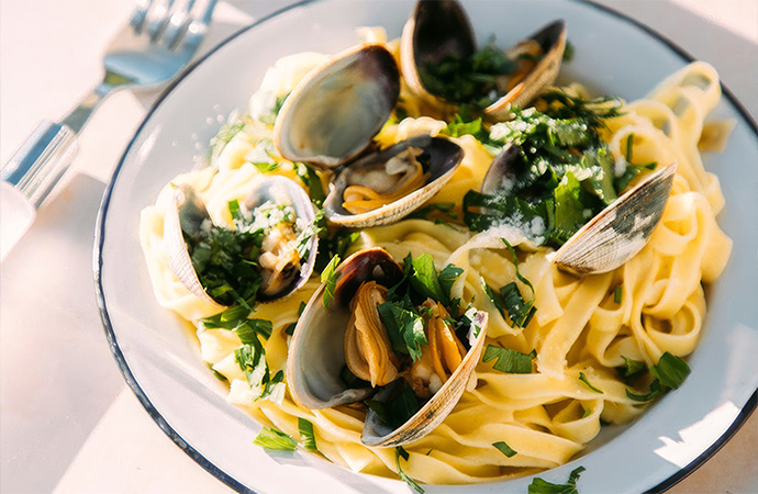 a plate of pasta with clams and parsley