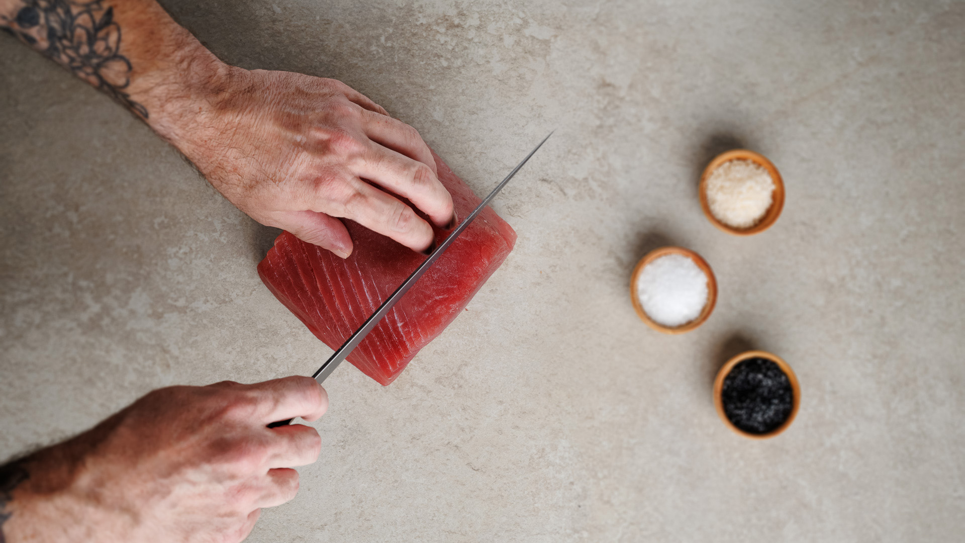 a person cutting a piece of tuna