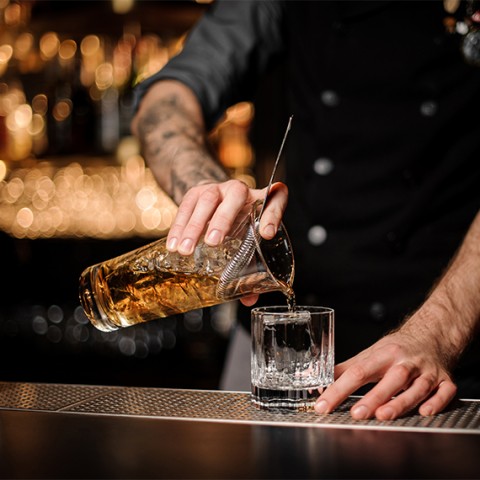 a person pouring a drink into a glass
