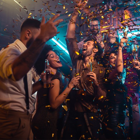 a group of people dancing in a room with confetti