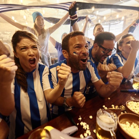 a group of people cheering at a table with food and drinks