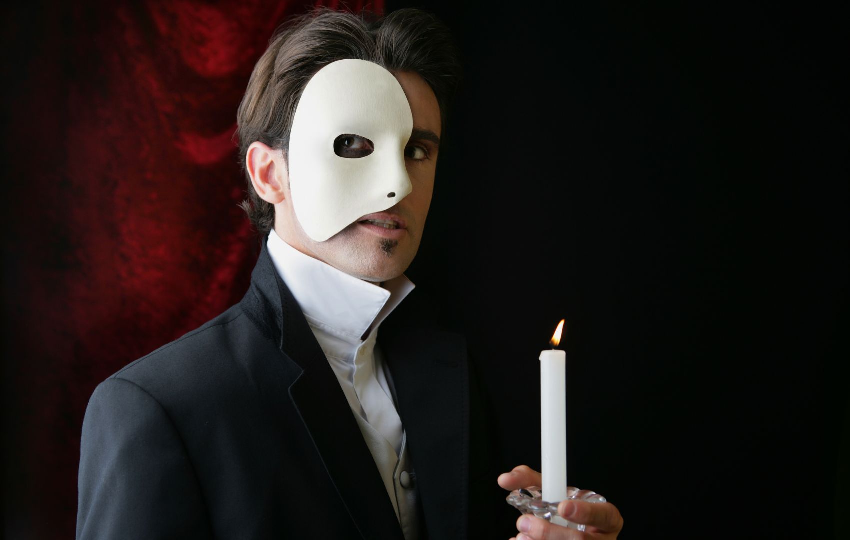 a man wearing a mask and holding a candle