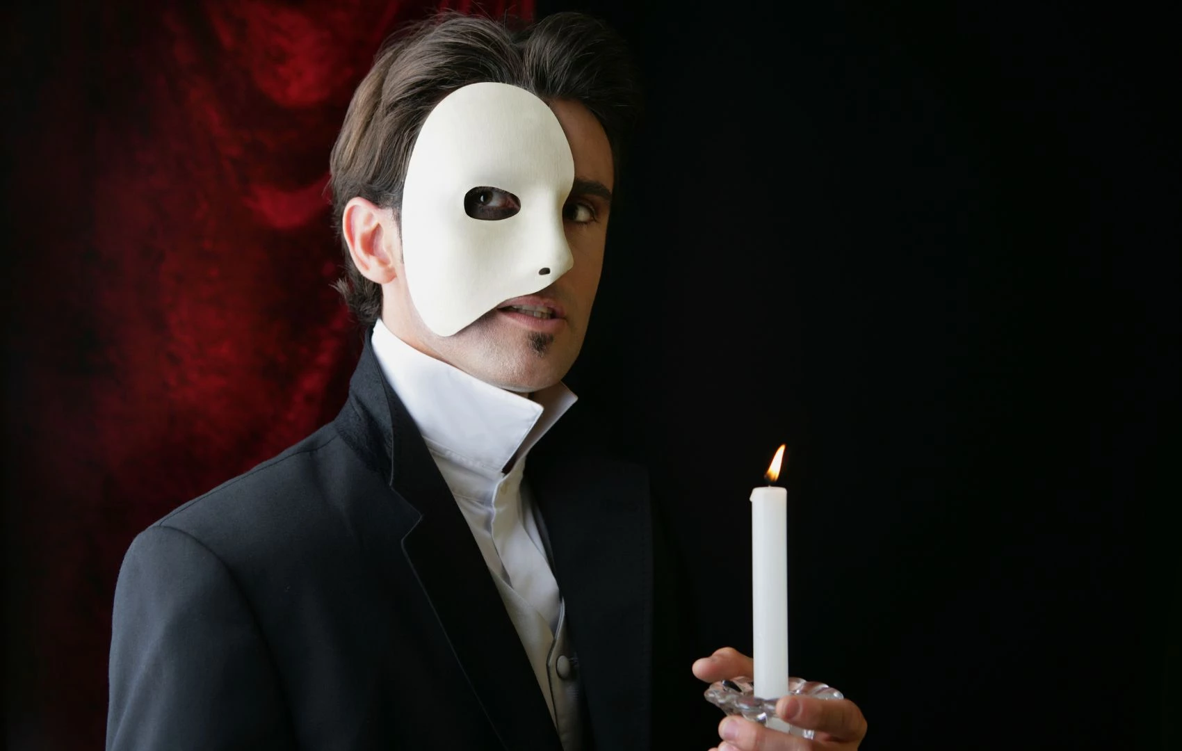 a man wearing a mask and holding a candle