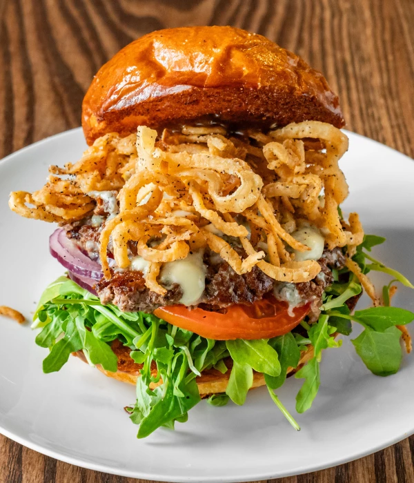 a burger with onions and lettuce on a white plate