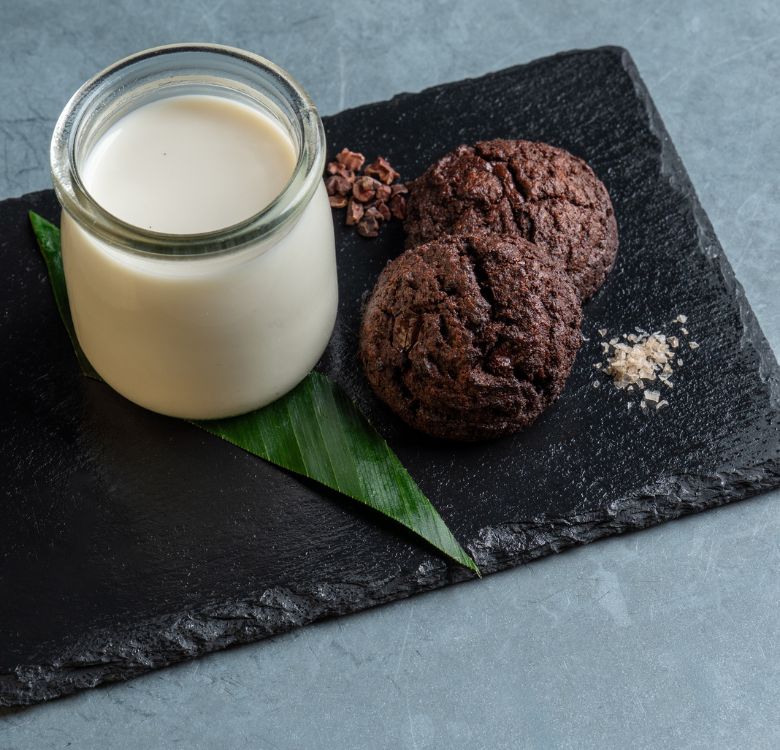 a glass jar of milk and cookies on a black plate