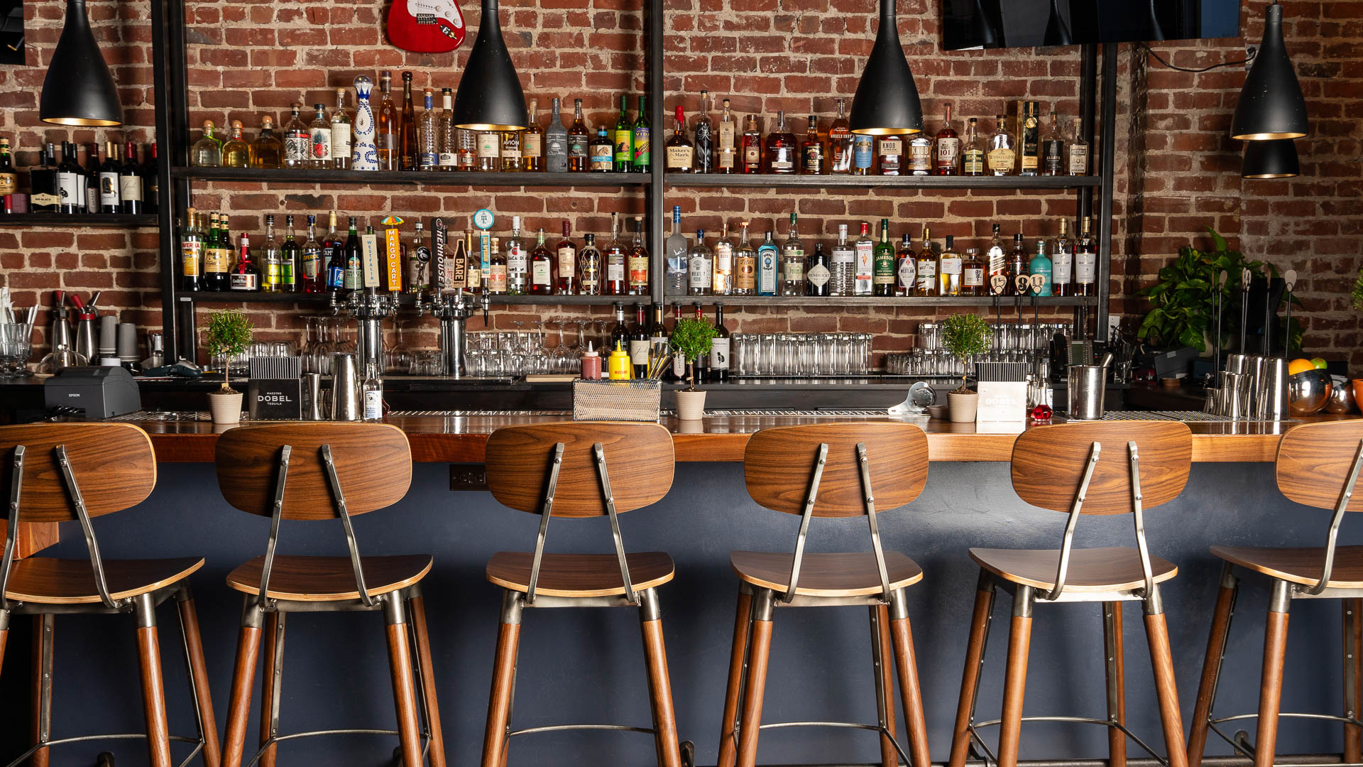 a bar with a row of chairs and bottles on the wall