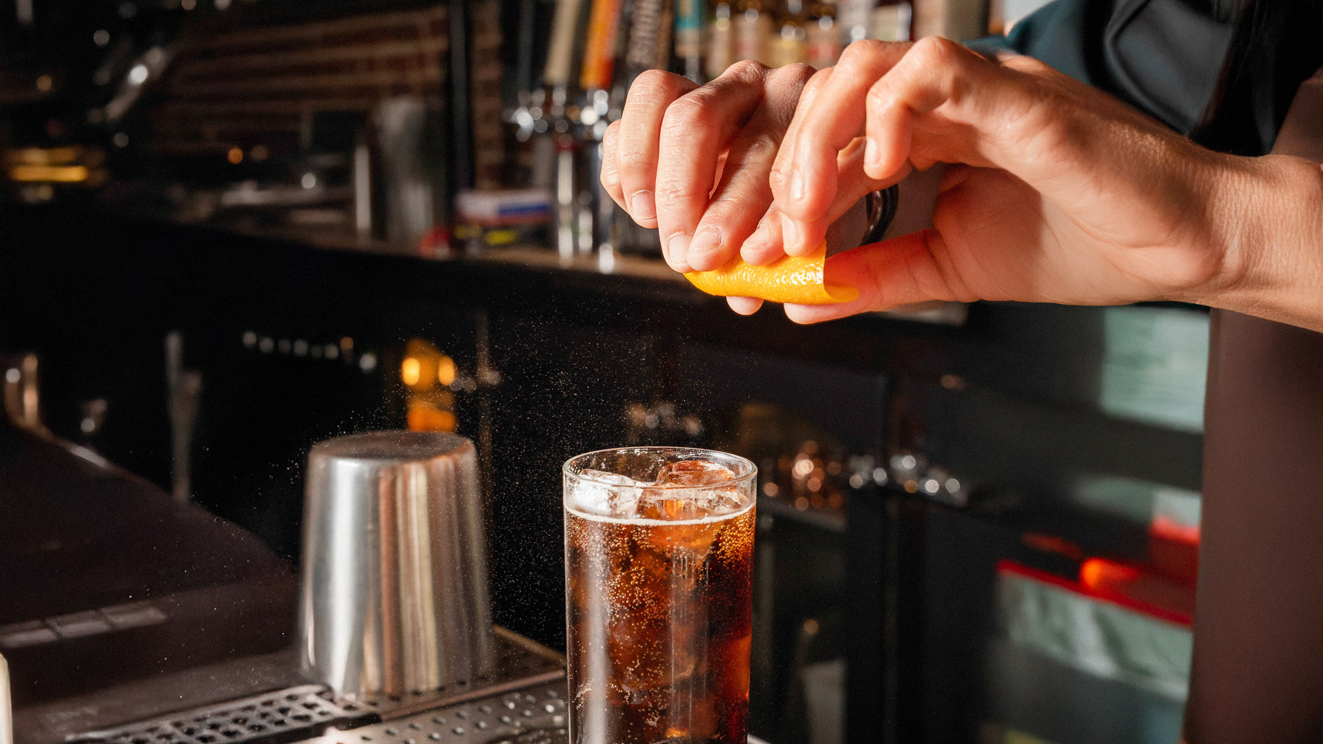 a person squeezing a lemon into a glass of liquid