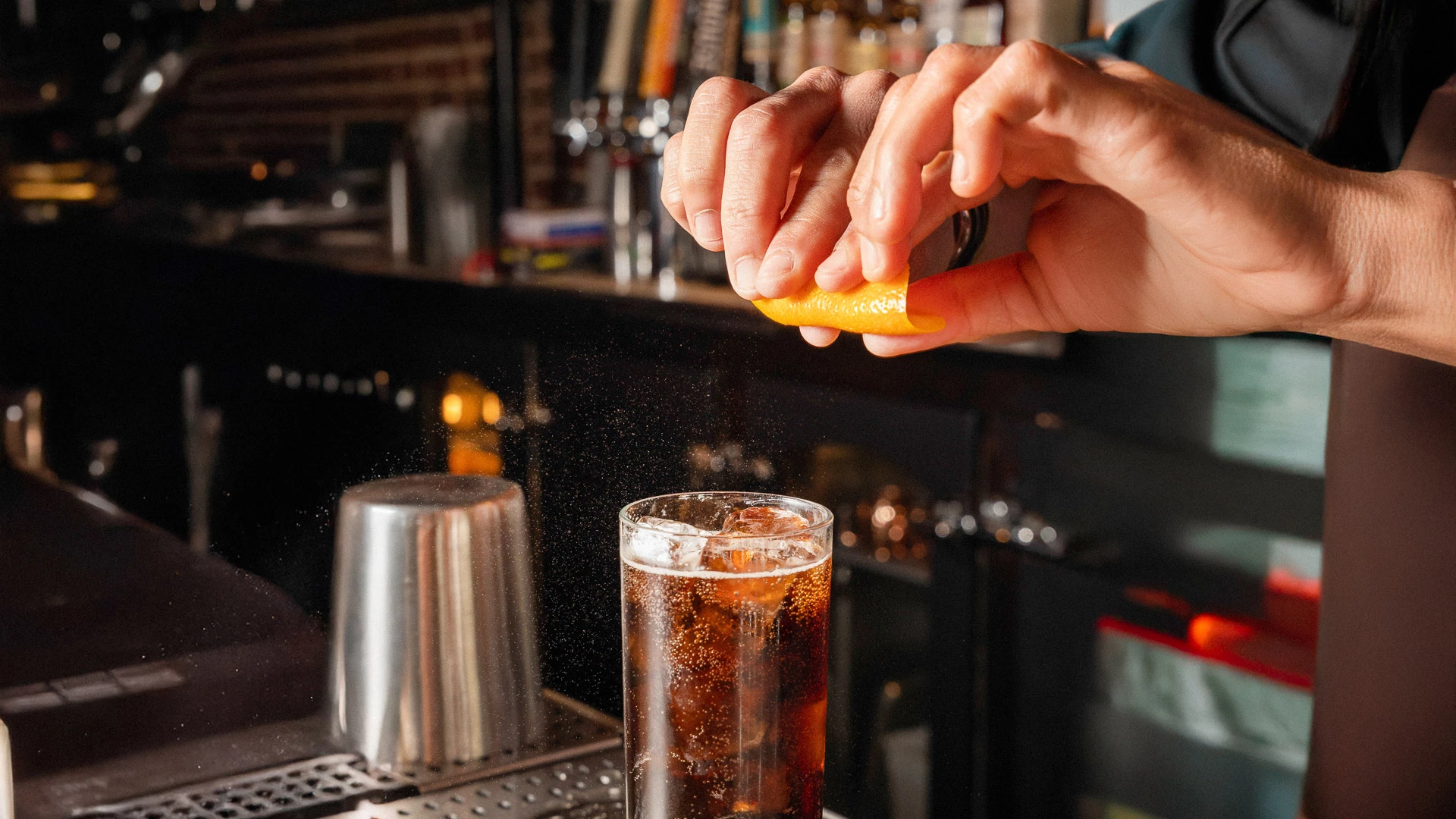 a person squeezing a lemon into a glass of liquid