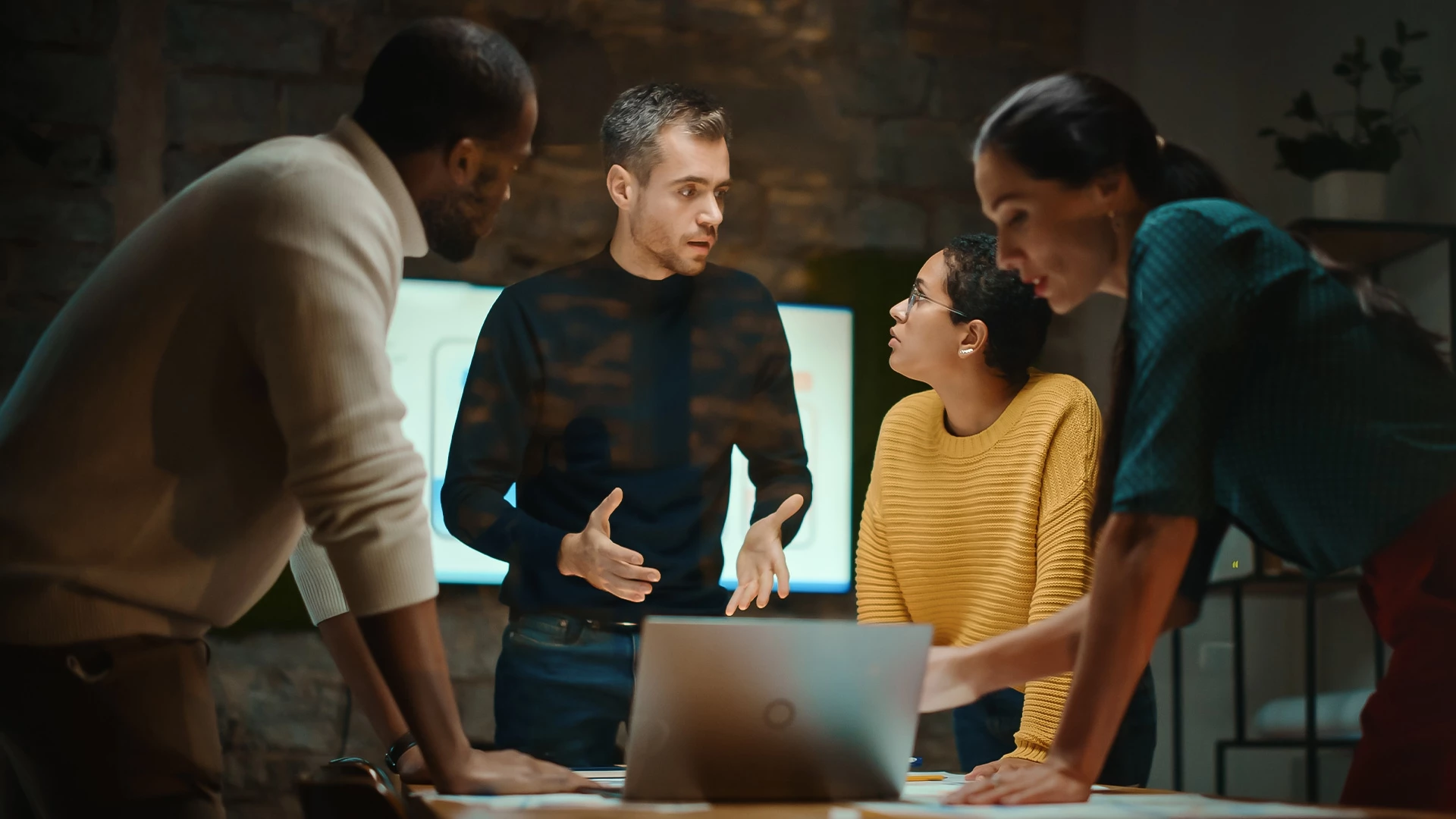a group of people standing around a table with a laptop