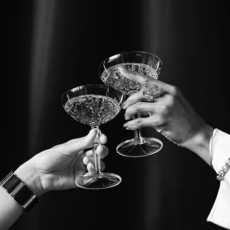 a pair of hands holding wine glasses