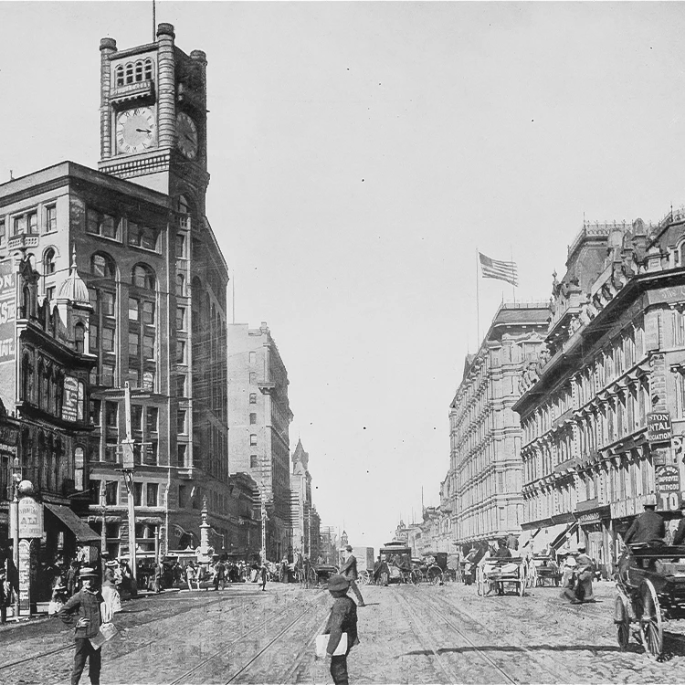 a street with a clock tower and horse drawn carriage