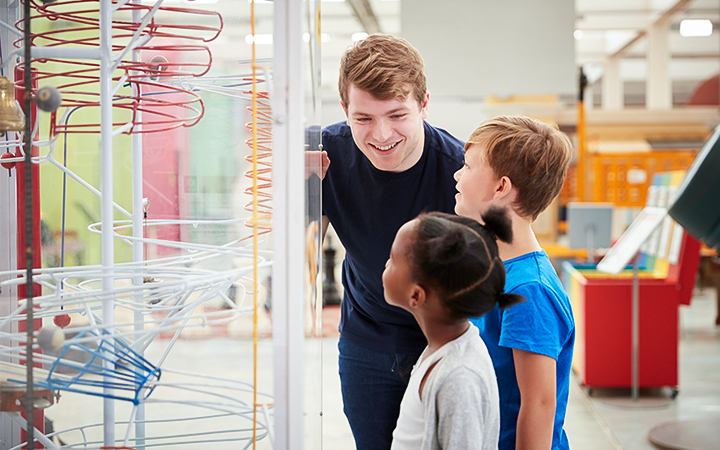 a man and children looking at a display