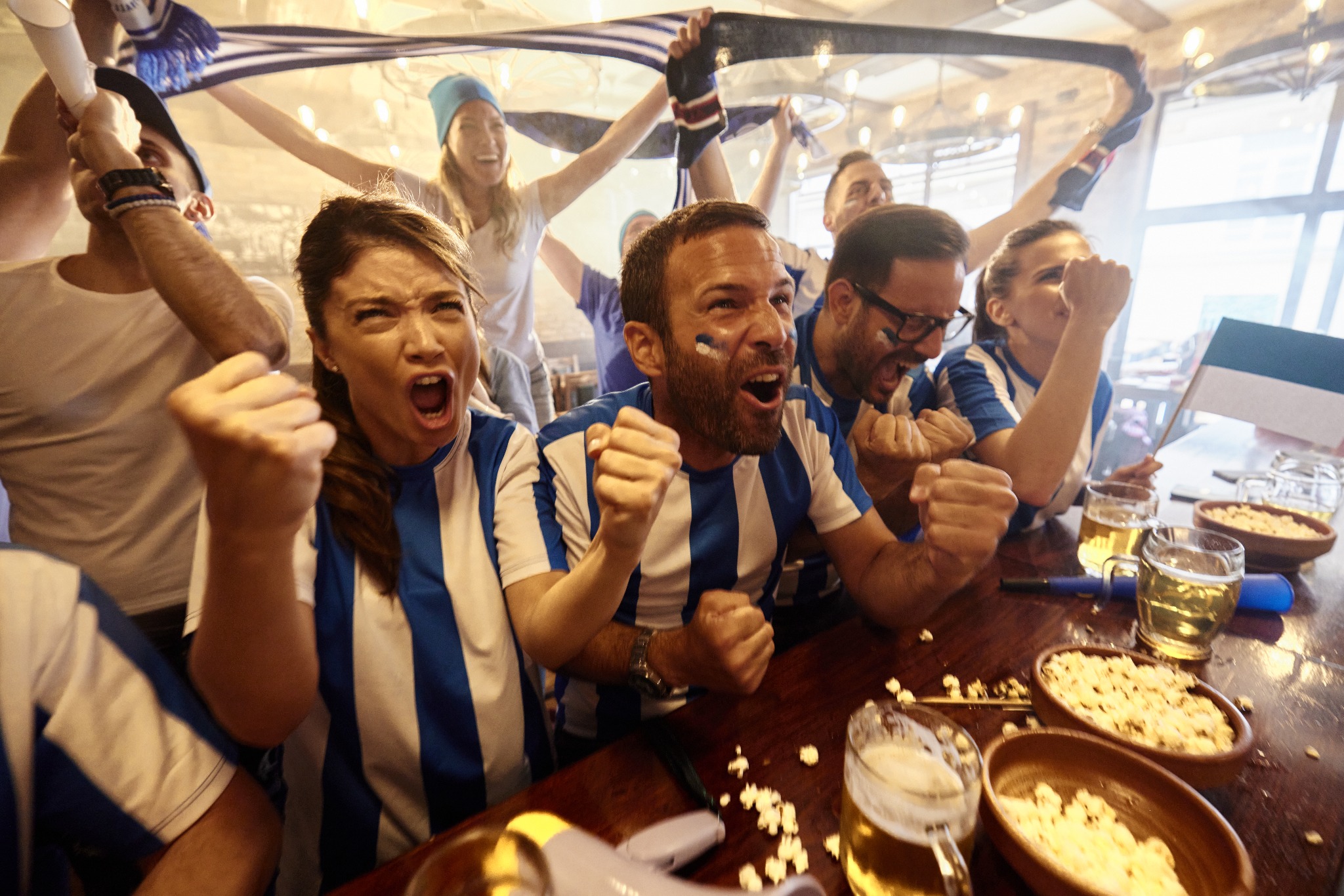a group of people cheering at a table with food and drinks