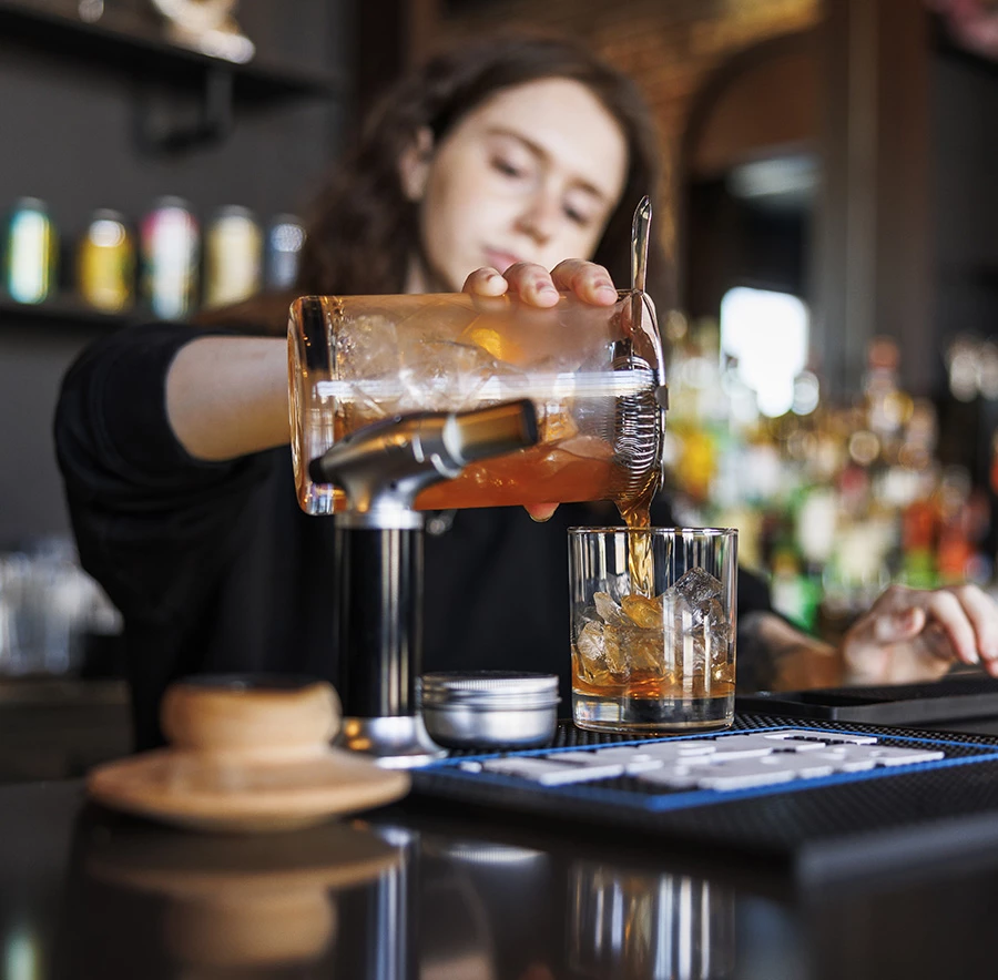a person pouring a drink into a glass