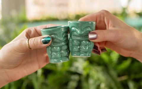 a pair of hands holding small green cups