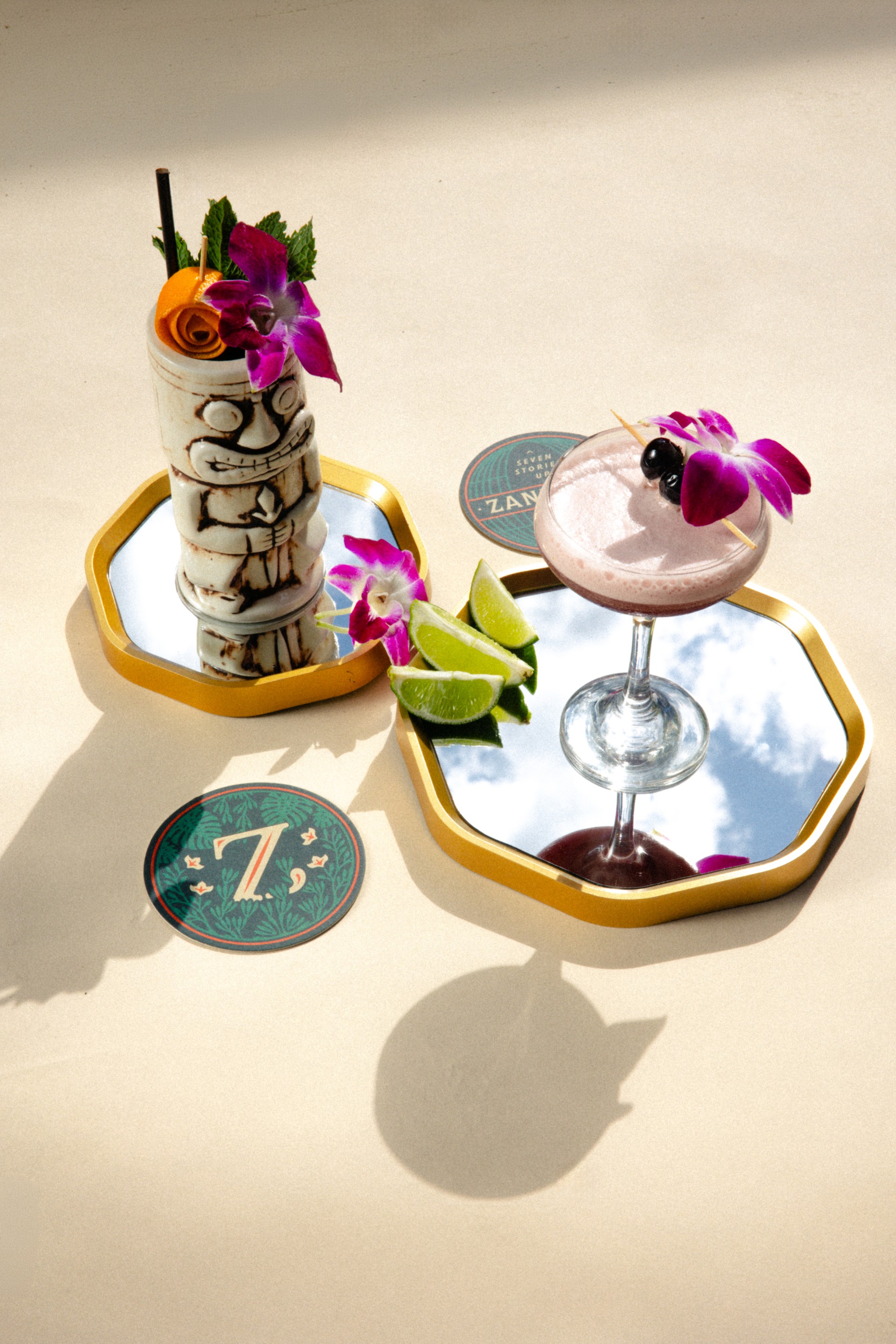 a cocktail with flowers and limes on a tray