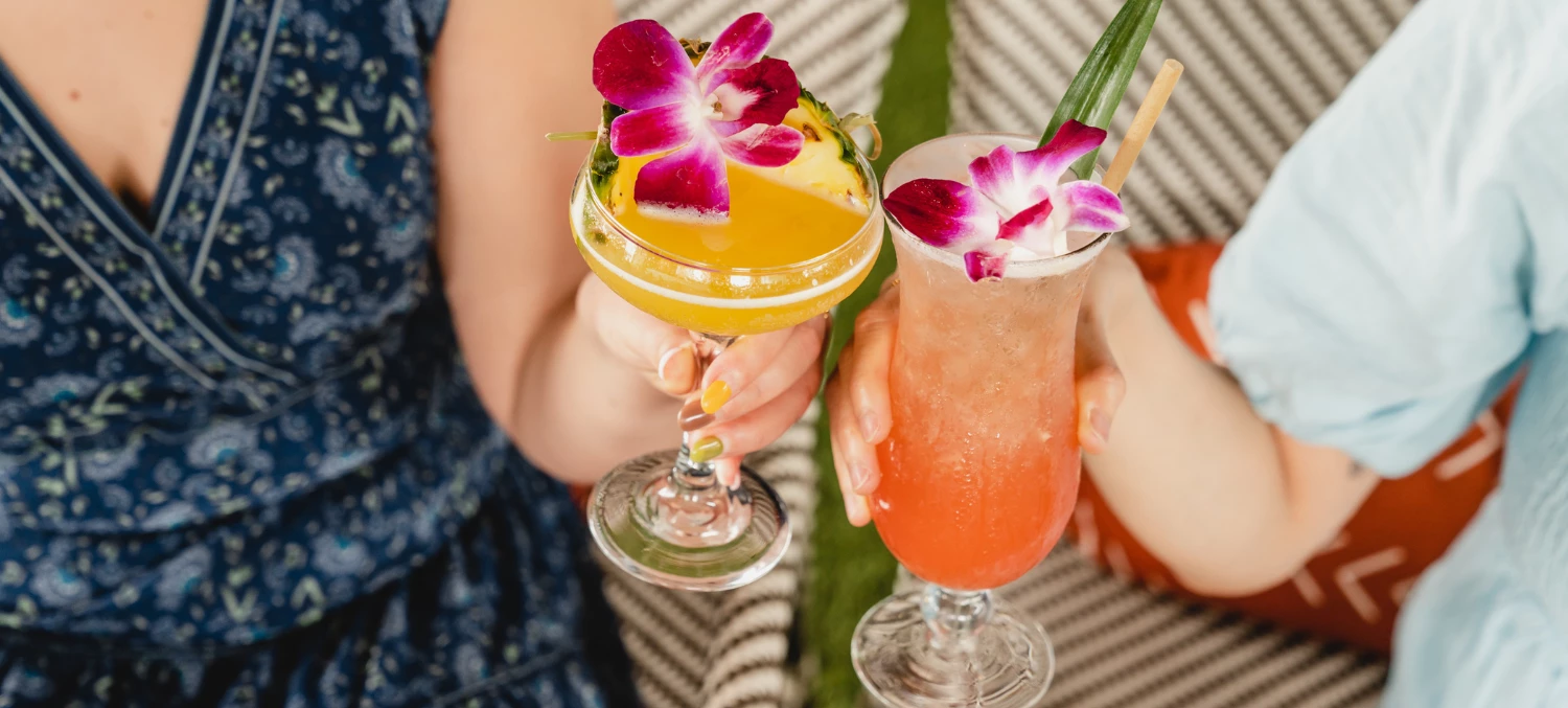 a woman holding up two glasses of drinks