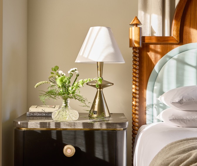 a lamp on a table next to a bed