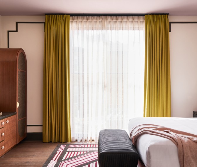 a room with a bed and a rug and curtains