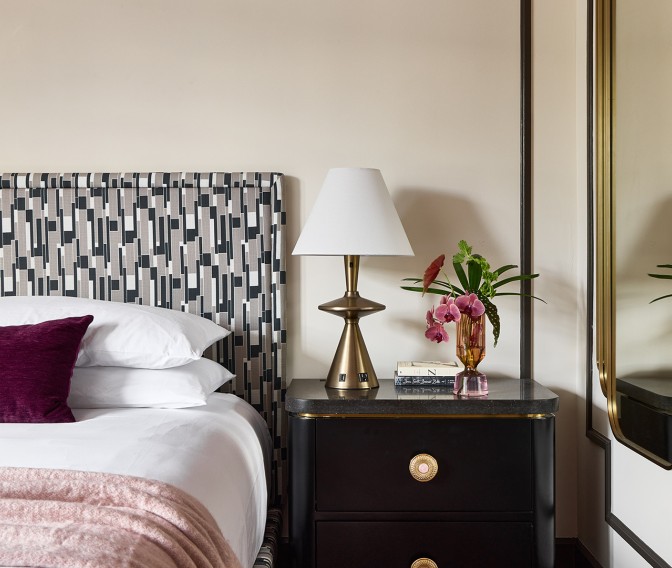 a nightstand with a lamp and flowers on it