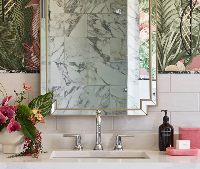 a bathroom sink with a mirror and flowers