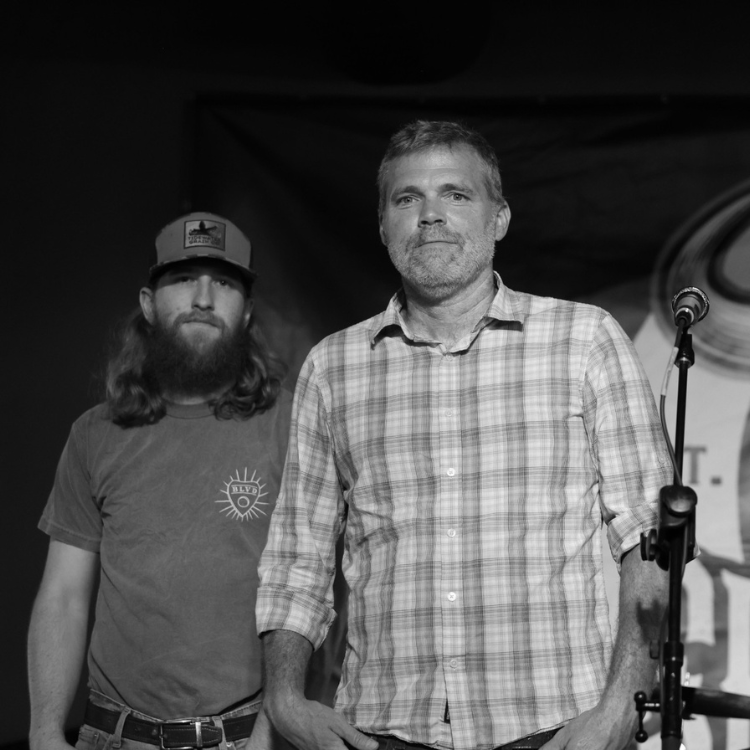 a man standing next to another man standing next to a microphone