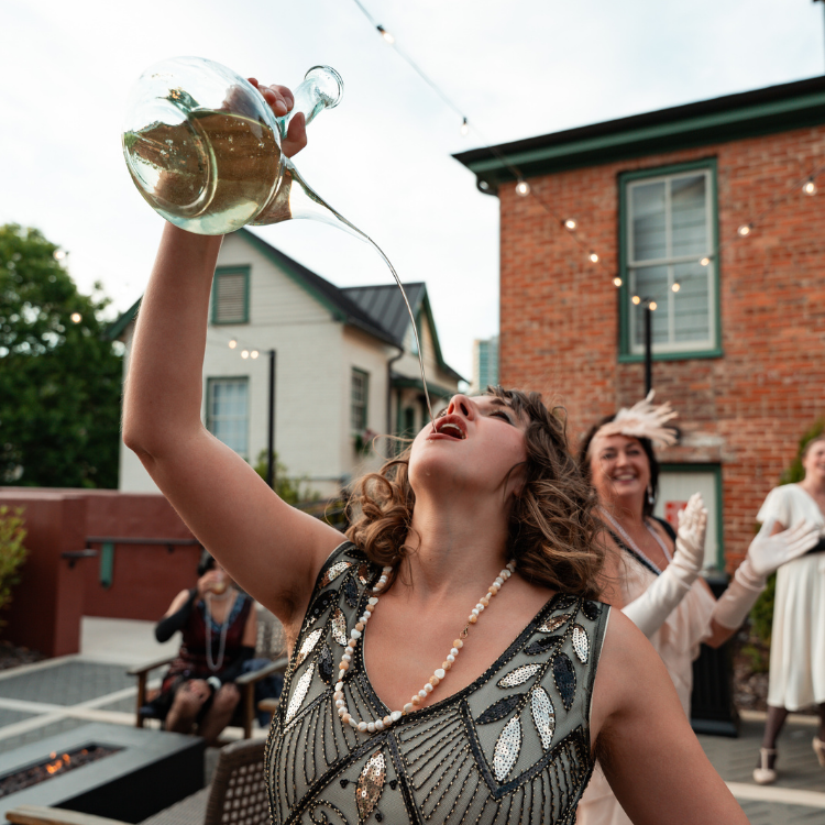 a woman pouring liquid into a glass bottle