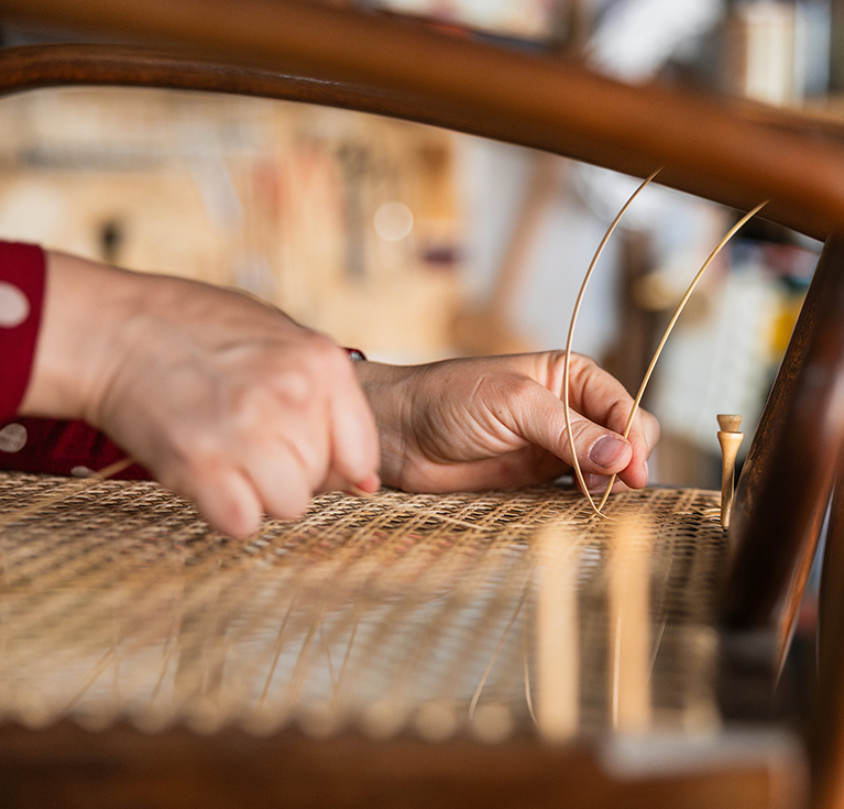 a person's hands sewing a piece of wood