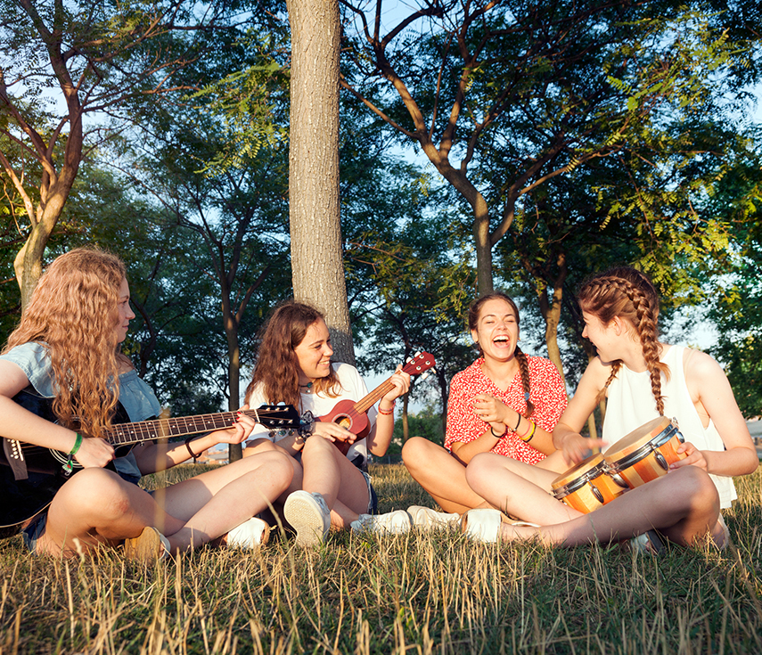 a group of girls sitting in grass playing instruments
