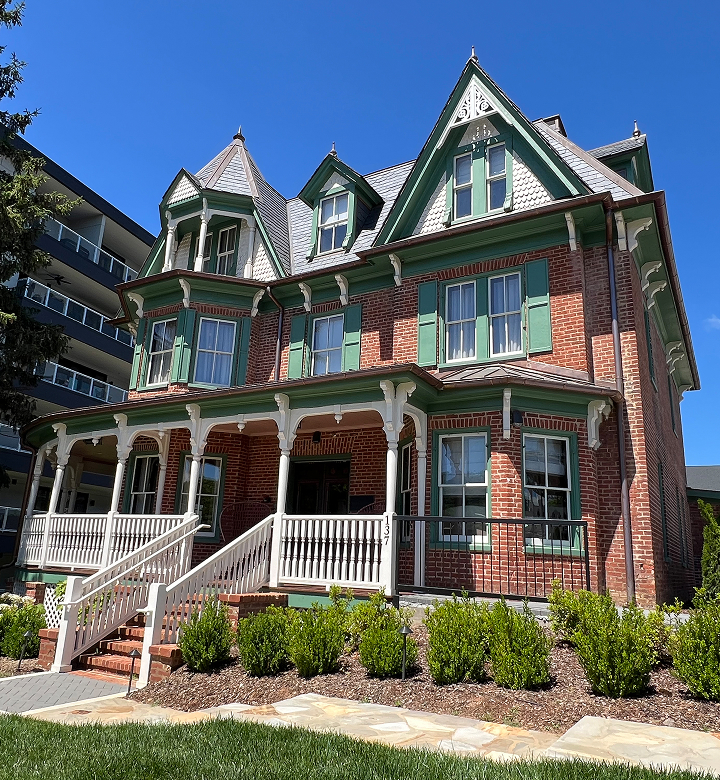 a brick house with green trim with Miramont Castle in the background