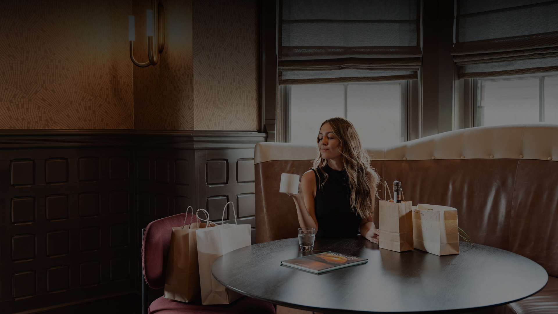a woman sitting at a table with a cup of coffee