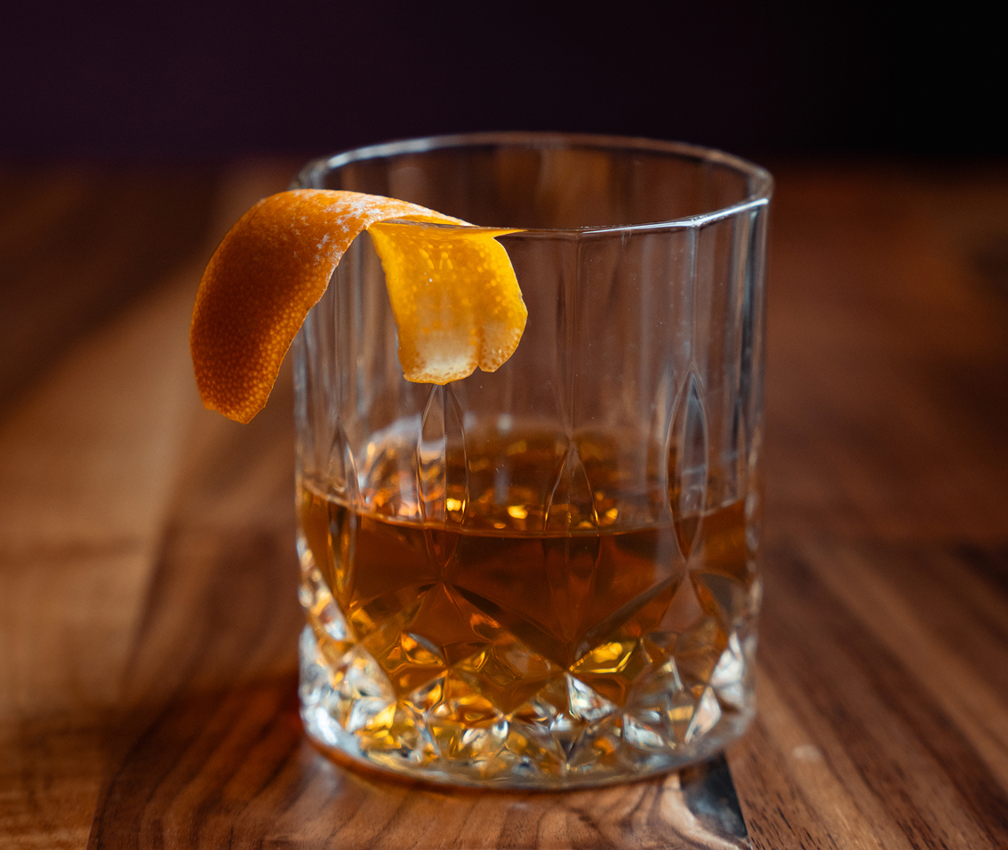 a glass with a drink and a peel