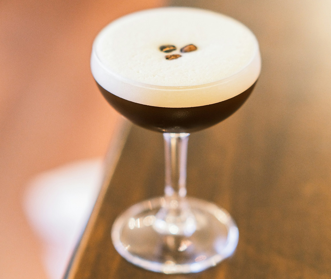 a glass with a brown liquid and a white foam on top