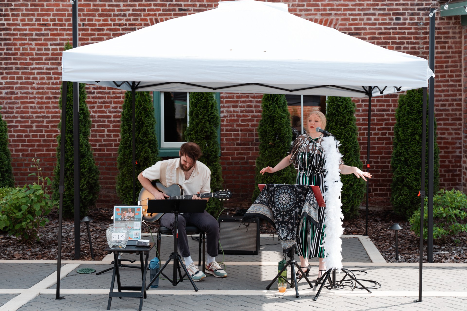 a man and woman playing instruments under a white tent