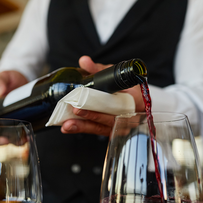 a person pouring wine into a glass