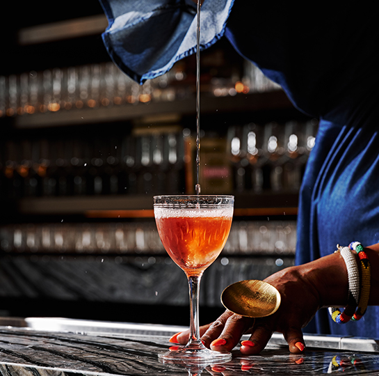 a person pouring a drink into a glass