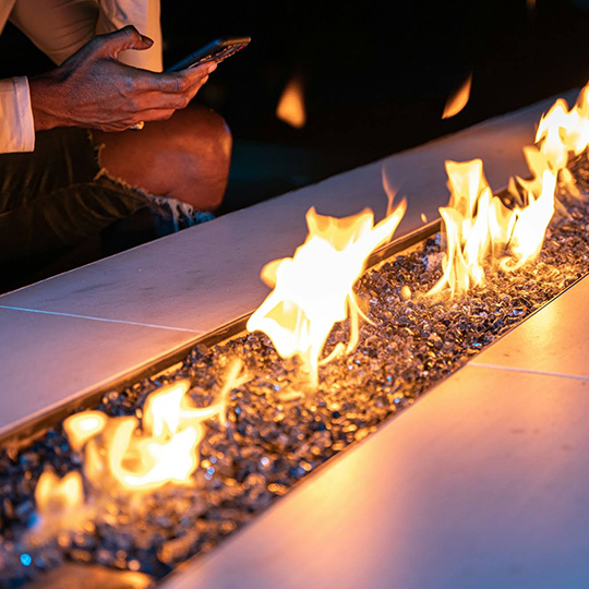 a person holding a phone next to a fire